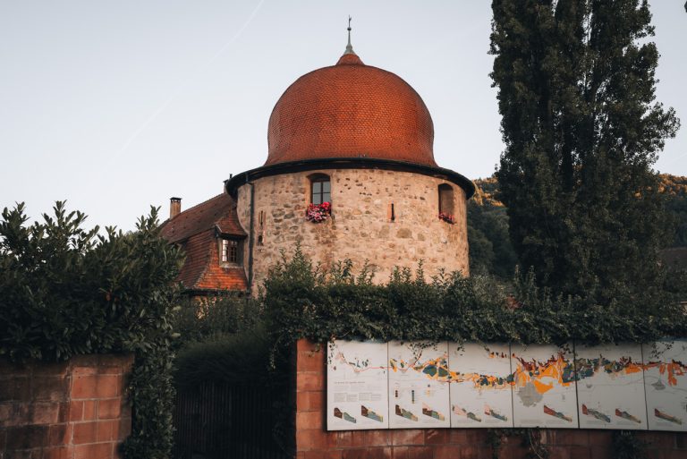 This is the southern end of the Alsace Wine Route in Thann. There is a small tower with a map of the wine route on a wall in front of it. It's a great day trip from Mulhouse.