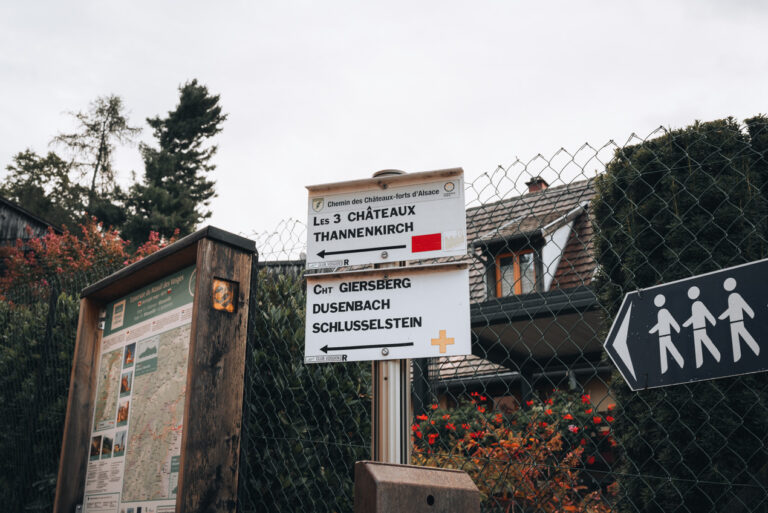 Starting point for the Three Castles of Ribeauvillé Hike. There is a sign with symbols and an arrow pointing to the direction of the trail.