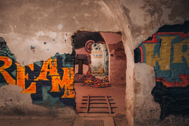 Letters and shapes are spray painted on a wall with a rainbow of colors. It's one example of street art at the MAUSA Vauban in Neuf-Brisach.