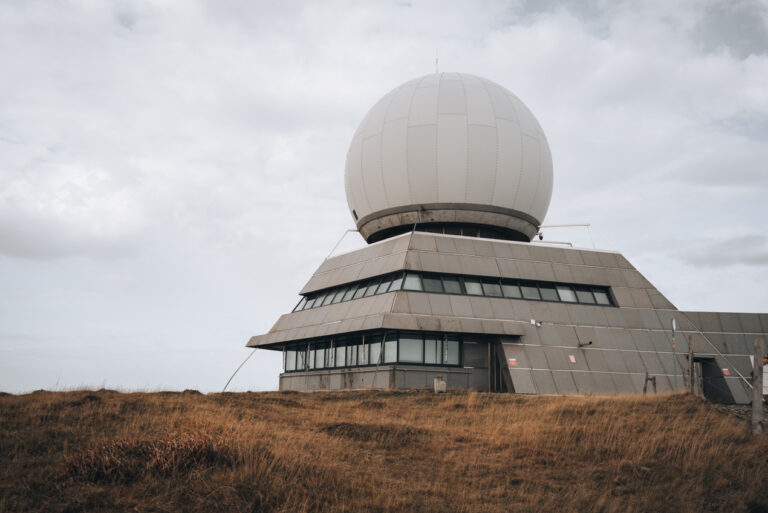 Summit of the Grand Ballon with a stone structure and a giant stone ballon on top. There is a terrace where people are looking out over the Vosges.