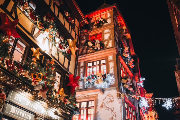 The Teddy Bear building on Rue du Maroquin decorated with huge teddy bears, lights, and Christmas ornaments at night.