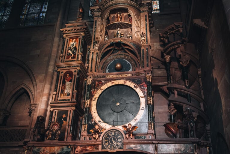 The Astronomical Clock in the Strasbourg Cathedral. Three dials are visible and there are figures on each side.