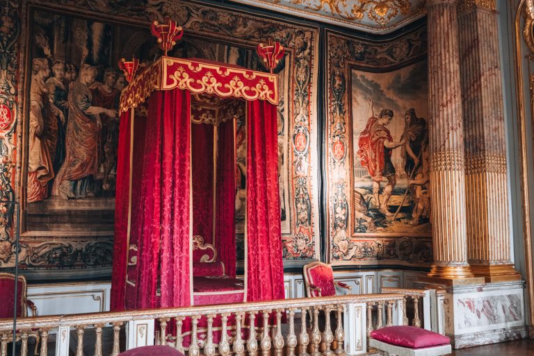 This is the King's Bedroom at the Museum of Decorative Arts in Strasbourg. There is a bed lined with drapes and its surrounded by murals painted on tapestries.