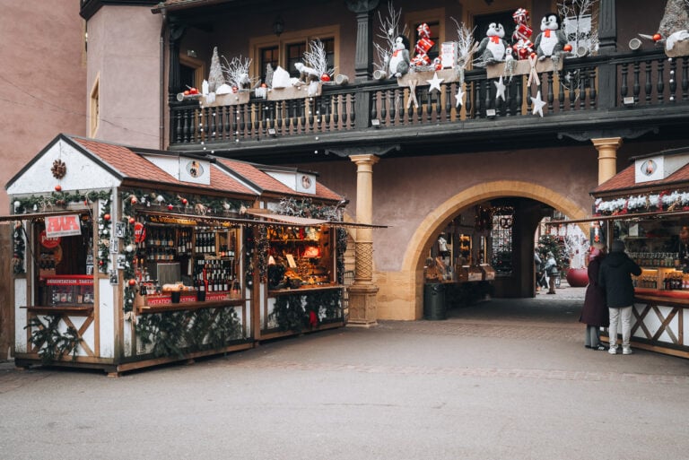 This is Koïfhus or Old Customs House in Colmar at Christmas. There are decorations and wooden stalls selling different Christmas related items.