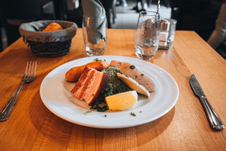 Plate of The Riquewihrienne served at Le Médieval restaurant in Riquewihr featuring a savory Alsatian sauerkraut with regional cuts of pork and potatoes.