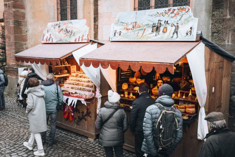 This is a set of two traditional wooden chalets at the Kaysersberg Christmas Market. Each one has a panel on top that is designed with a Christmas theme.