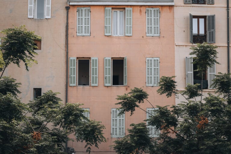 This is the view from the Traverse Font de Caylus in Le Panier. It's a photo of an apartment building. There are several windows and the bottom is covered by towering trees.