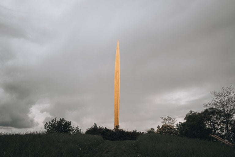 This is the Tremblement de Ciel in the Jardins Jean Marie Pelt Parc de la Seille. It's a large statue pointing to the sky and it's surrounding by lush green gardens.