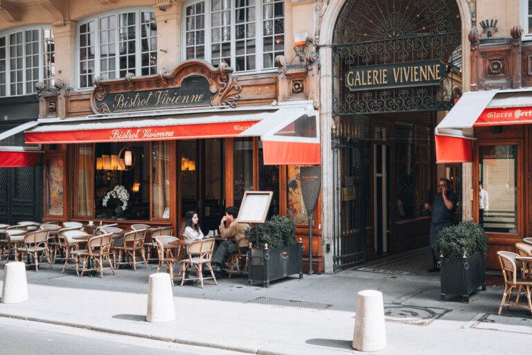 Typical cafe in Paris with people sitting at tables talking over coffee and croissants. This is one of the reasons why people adore the Paris.