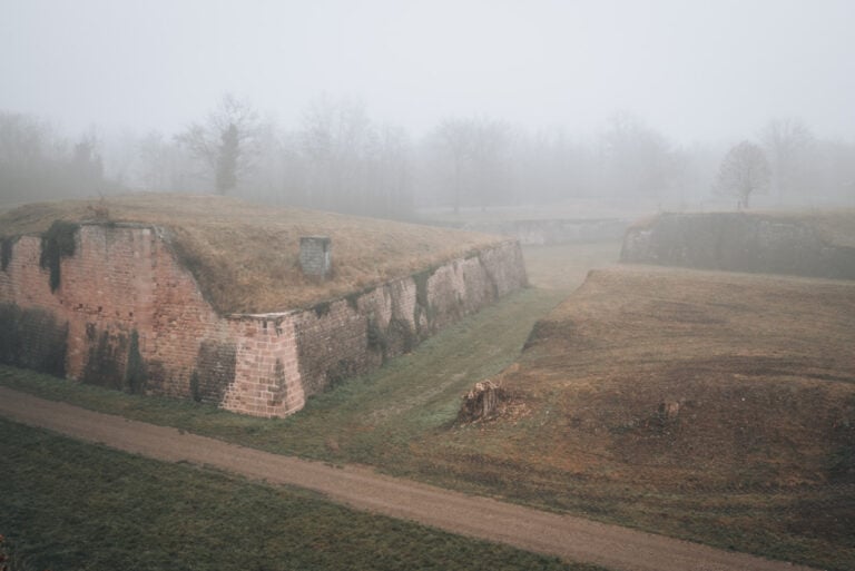 Bird's eye view of the Vauban fortification in Neuf-Brisach. There dirt roads running between large stone walls as fog rolls over the top.