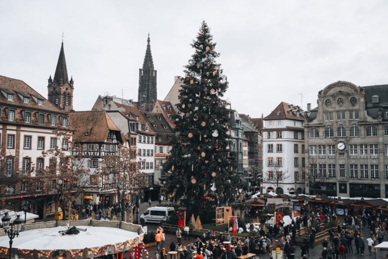 Panoramic view of the towering Christmas tree in Place Kléber seen from the Aubette overlooking Strasbourg's festive market square. The illuminated centerpiece is one of the most iconic things to see in December.