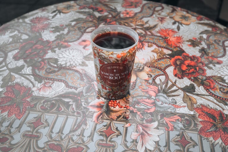 This is a cup of vin chaud from the Christmas market in the town of Mulhouse. The cup and the table it is on are both designed with the Christmas fabric.