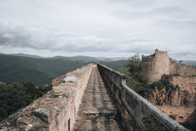 Stone walking path along the upper terraces of the Château du Hohlandsbourg bordered by fortress walls and scenic viewpoints. Exploring the castle ramparts is a memorable part of the visit.