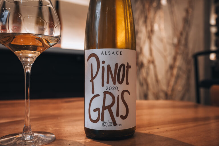 A bottle of pinot gris next to a glass of pinot gris, both from my wine tasting at Domaine Martin Jund in Colmar.