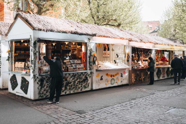 Wooden Chalets at the Easter Market in Colmar. They are topped with hay and decorated with festive ornaments. The Easter market is one of the must-see events in Colmar.