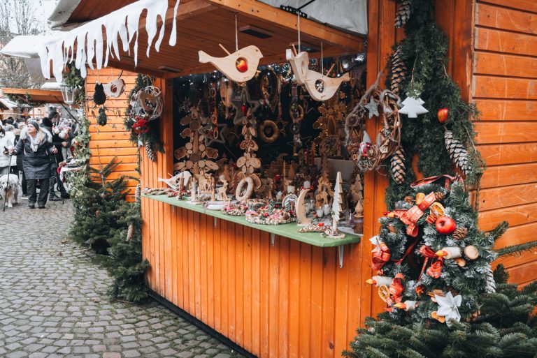 This is a wooden Christmas market stall in Eguisheim. It's decorated with wreaths and there are handmade wooden ornaments being sold.